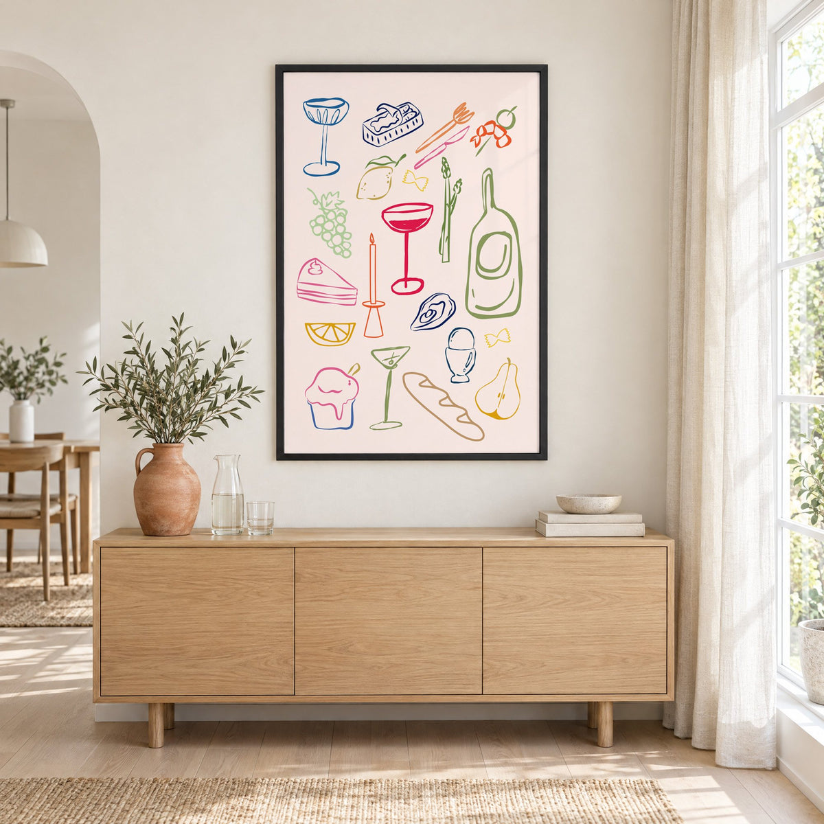 Line art candle coupe dinner party print in a black frame above an oak sideboard with a terracotta vase of olive branches