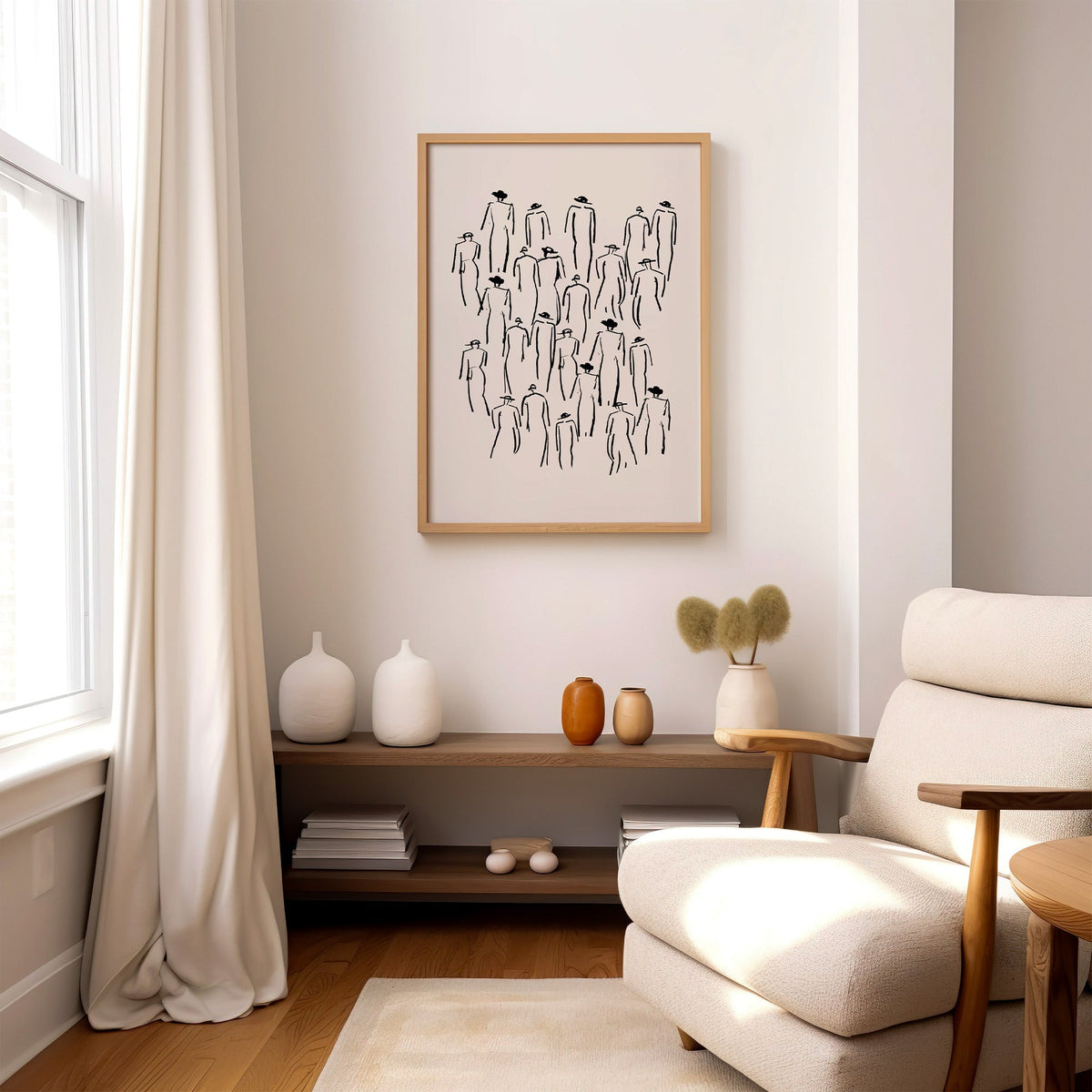 Crowd of hat-wearing figures line art print in an oak frame above a wood console shelf by a cream boucle armchair