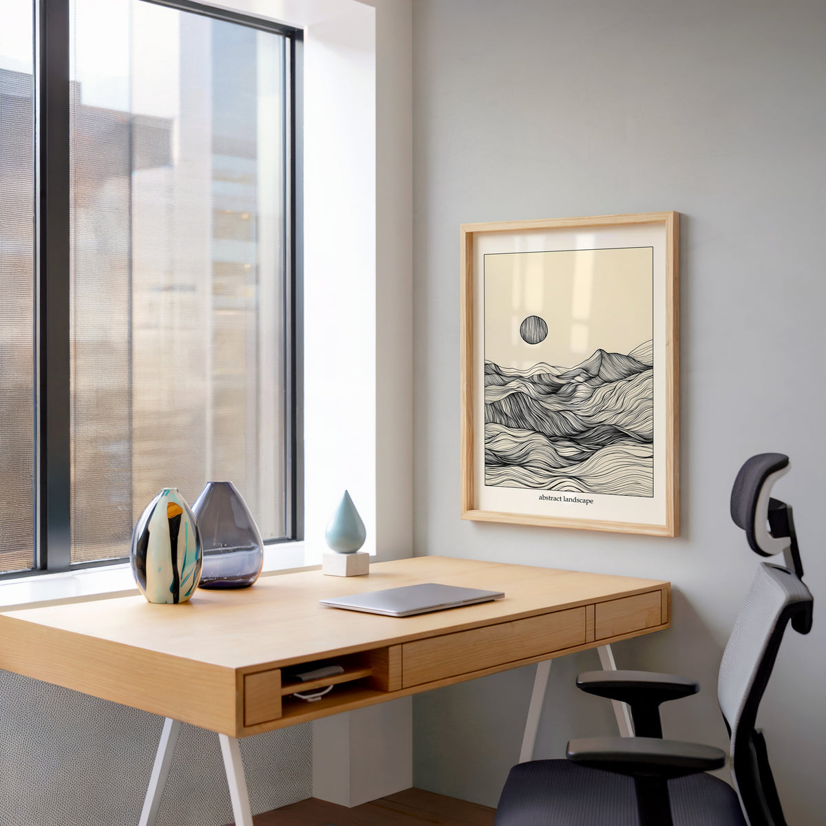 Line art mountain and sun abstract landscape print in a pale wood frame above a home office desk by a tall window