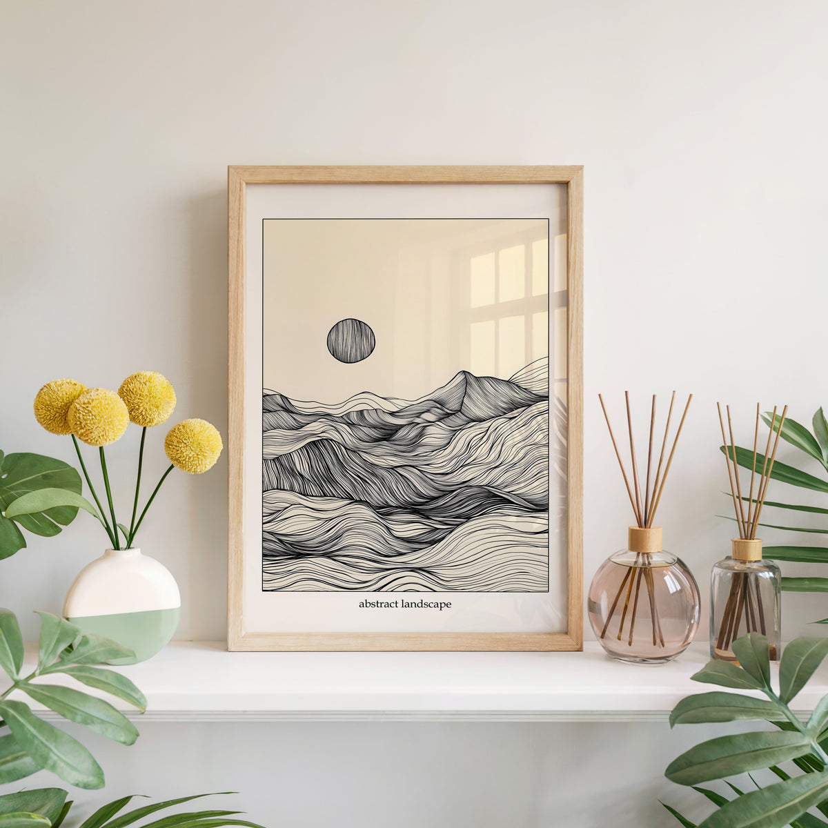 Line art mountain and sun abstract landscape print in a light oak frame leaning on a white mantel with yellow flowers