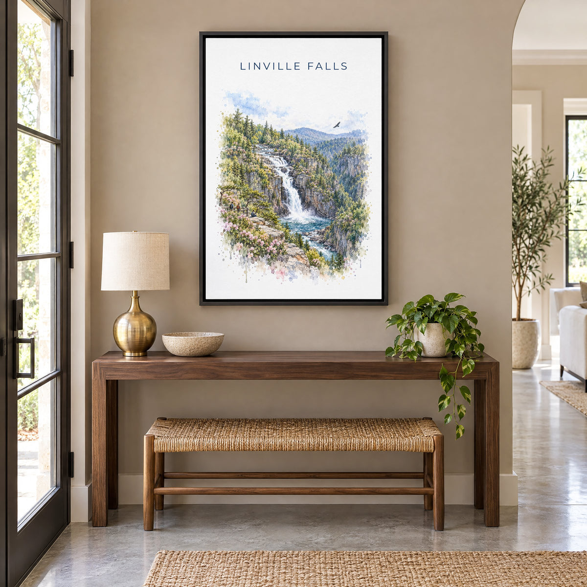 Linville Falls watercolor print as a black floater canvas above a walnut console and woven bench in an entryway