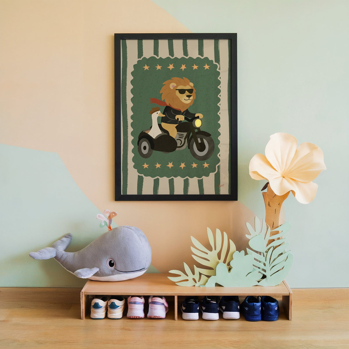 Lion on motorcycle with goose sidecar nursery print in a black frame on a mint and peach wall above a whale plush