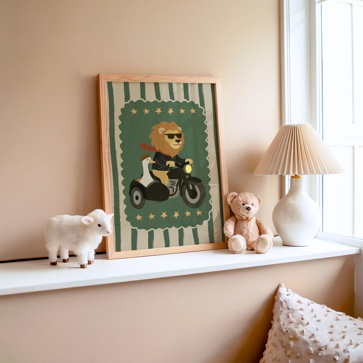 Lion on motorcycle with goose sidecar nursery print in an oak frame on a window ledge with a toy lamb and teddy