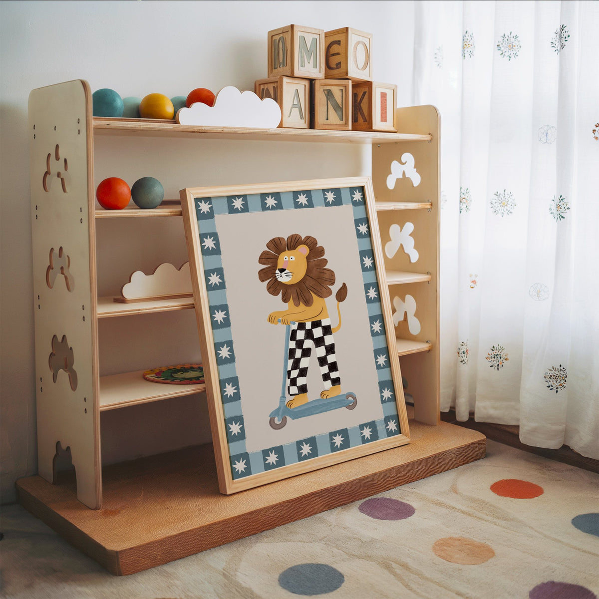 Lion on scooter in checkered pants nursery print in an oak frame leaning on a toy shelf with wooden letter blocks