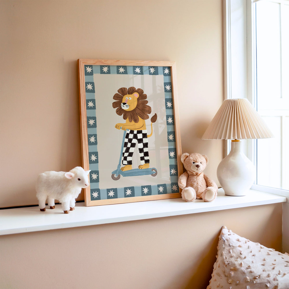 Lion on scooter in checkered pants nursery print in an oak frame on a window ledge with a toy lamb and teddy