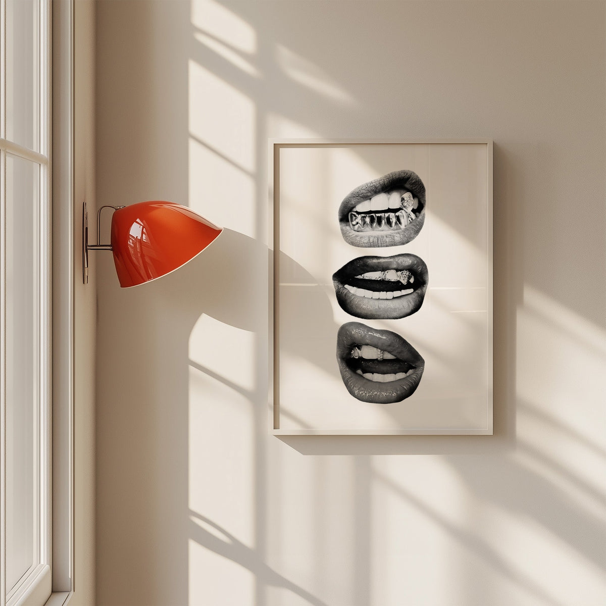 Three lips with jeweled metal grills print in a white frame on a sunlit wall beside a red sconce