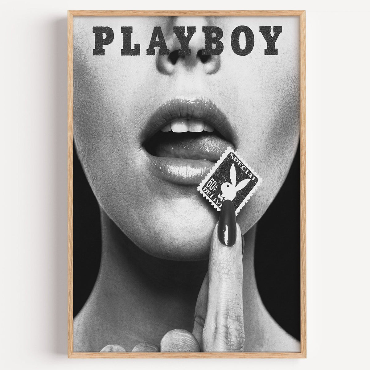 Glossy lips with postage stamp on black print in a light oak frame on a plain white wall