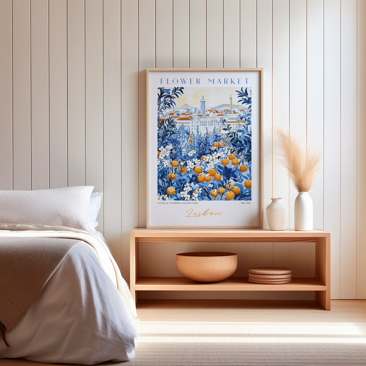 Lisbon flower market print in an oak frame on a wood bench against a white shiplap bedroom wall with pampas grass