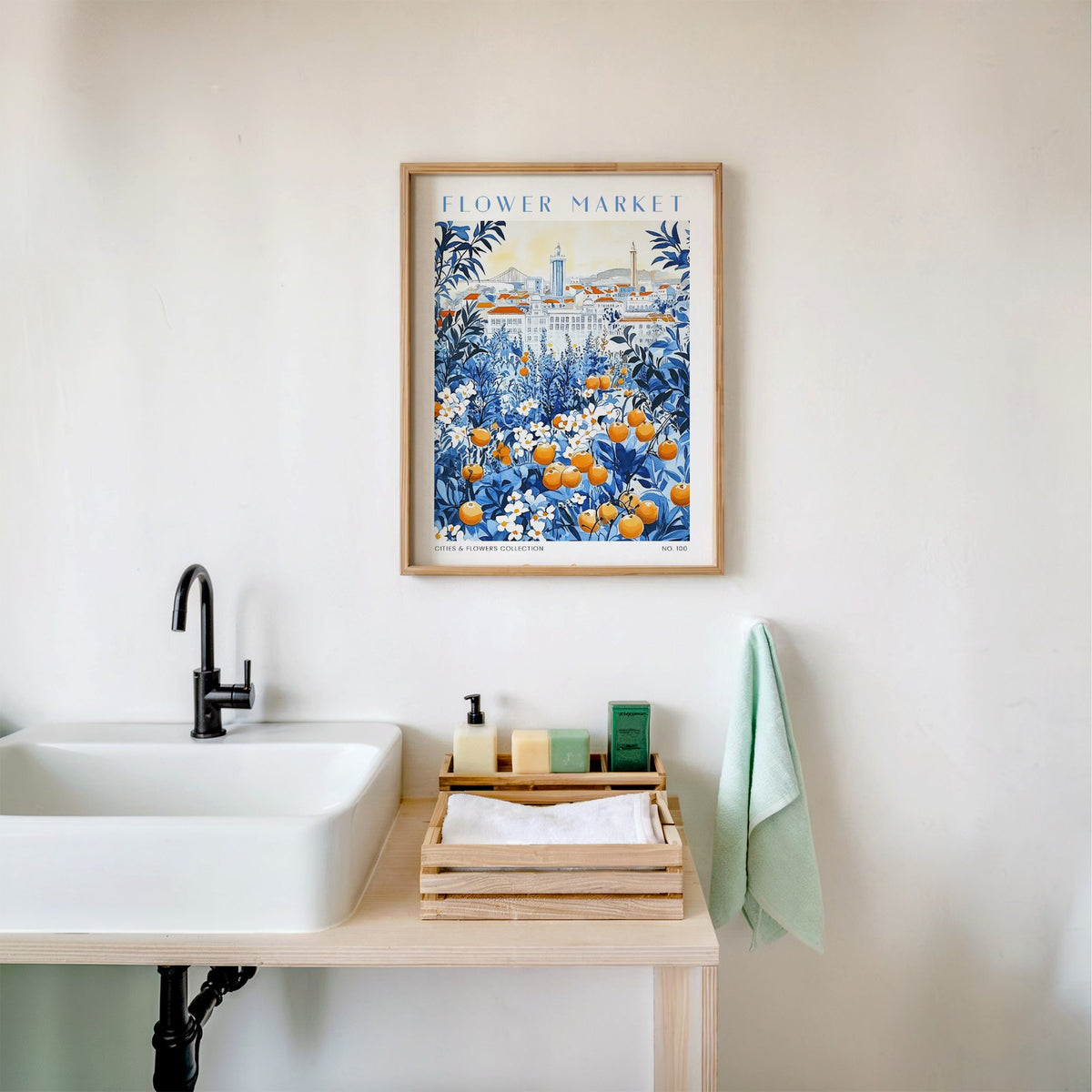 Lisbon flower market print in an oak frame above a white bathroom sink with folded towels