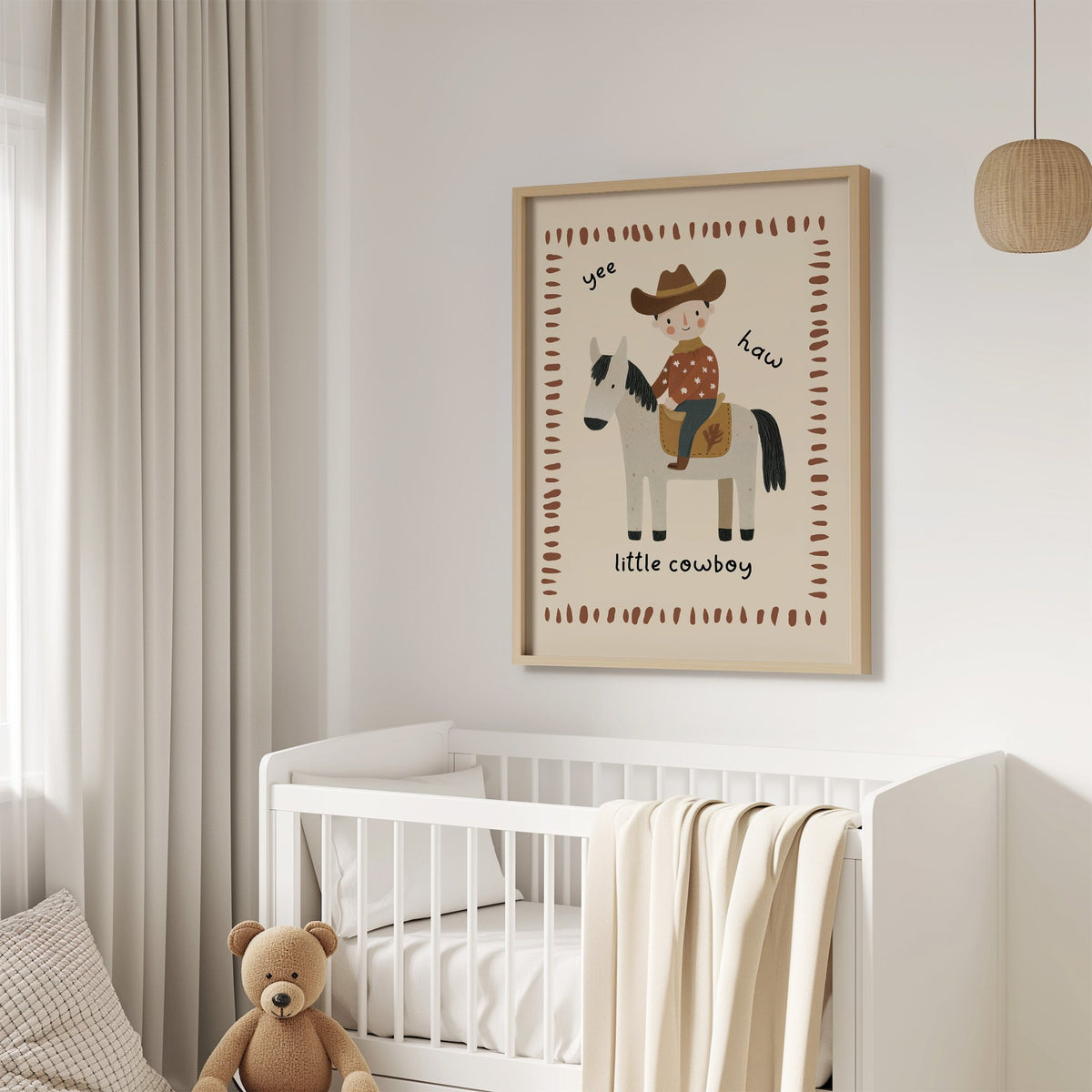 Little cowboy on horse yee haw nursery print in an oak frame above a white crib with a teddy bear