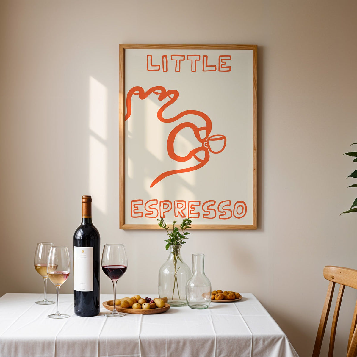 Little espresso one line print in an oak frame above a table laid with red wine and glasses