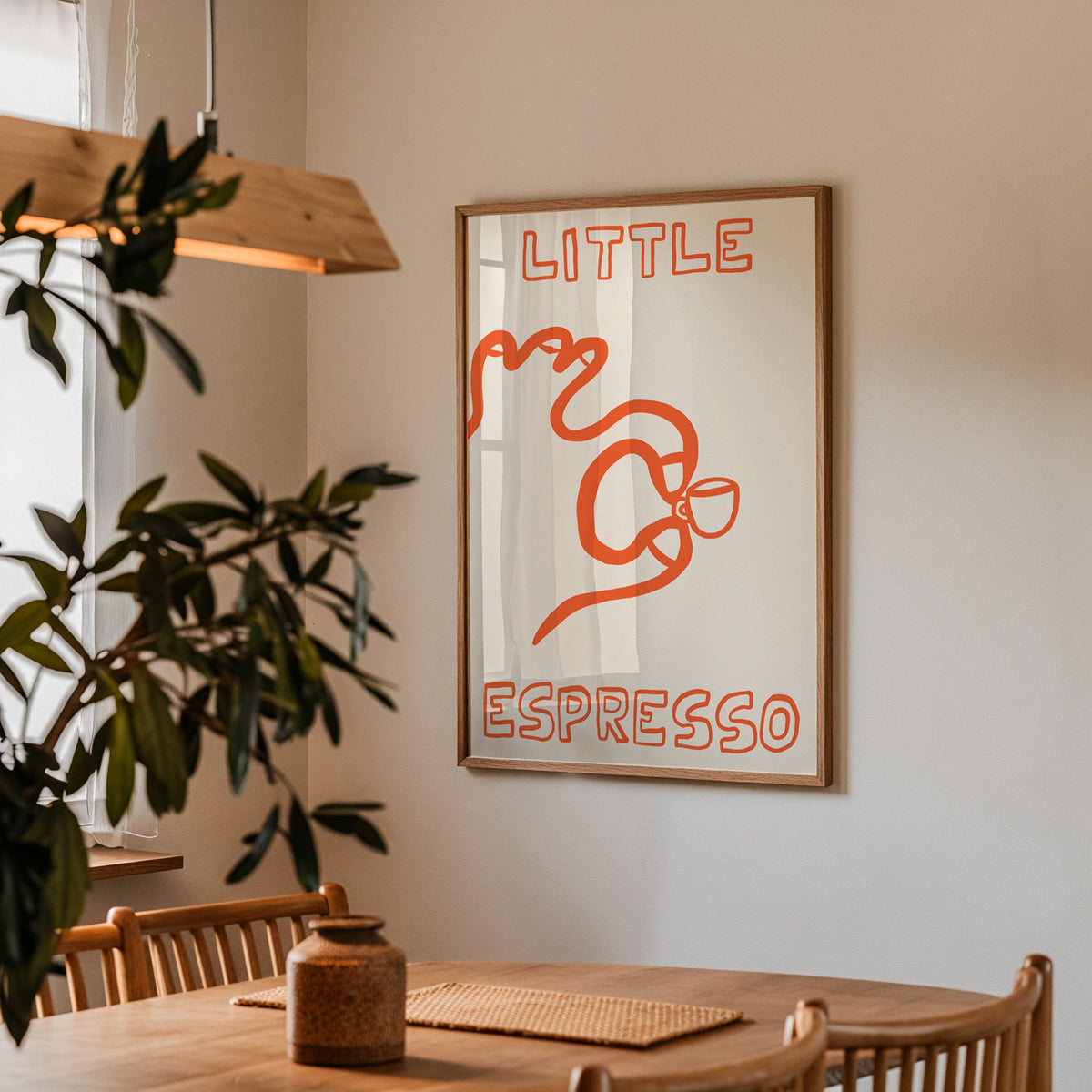 Little espresso one line print in a walnut frame above a dining table beside an olive tree
