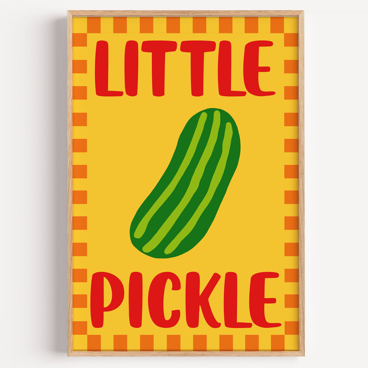 Little pickle print in a light oak frame on a plain white wall