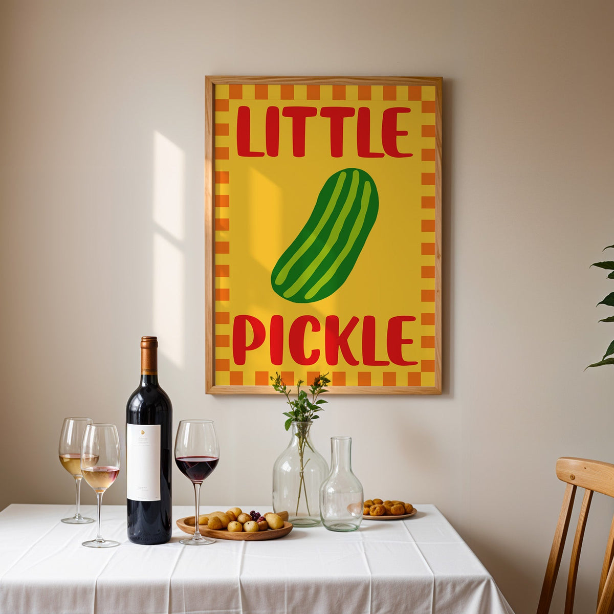 Little pickle print in an oak frame above a table laid with red wine and glasses