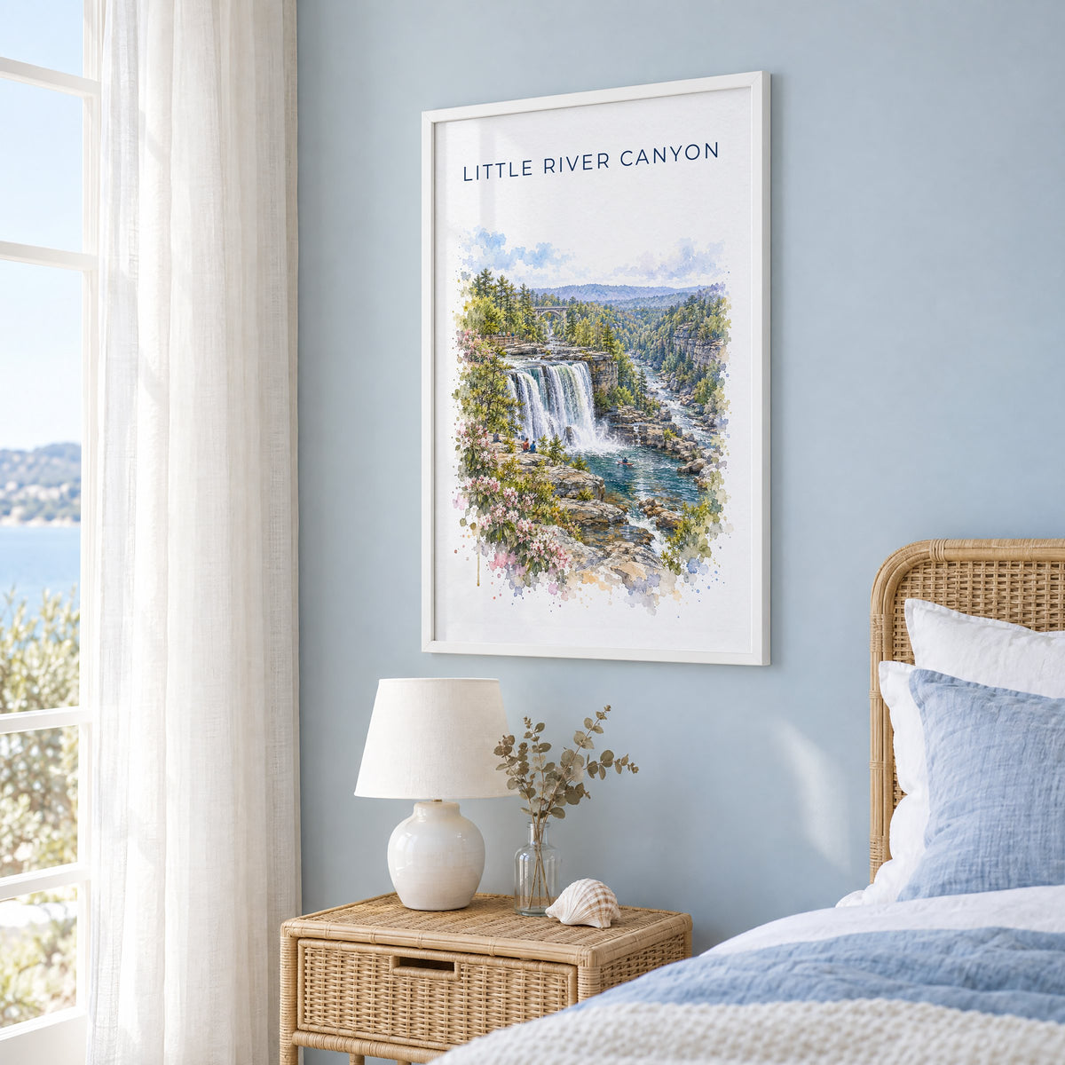 Little River Canyon National Preserve watercolor in a white frame on a pale blue wall beside a rattan bed in a coastal