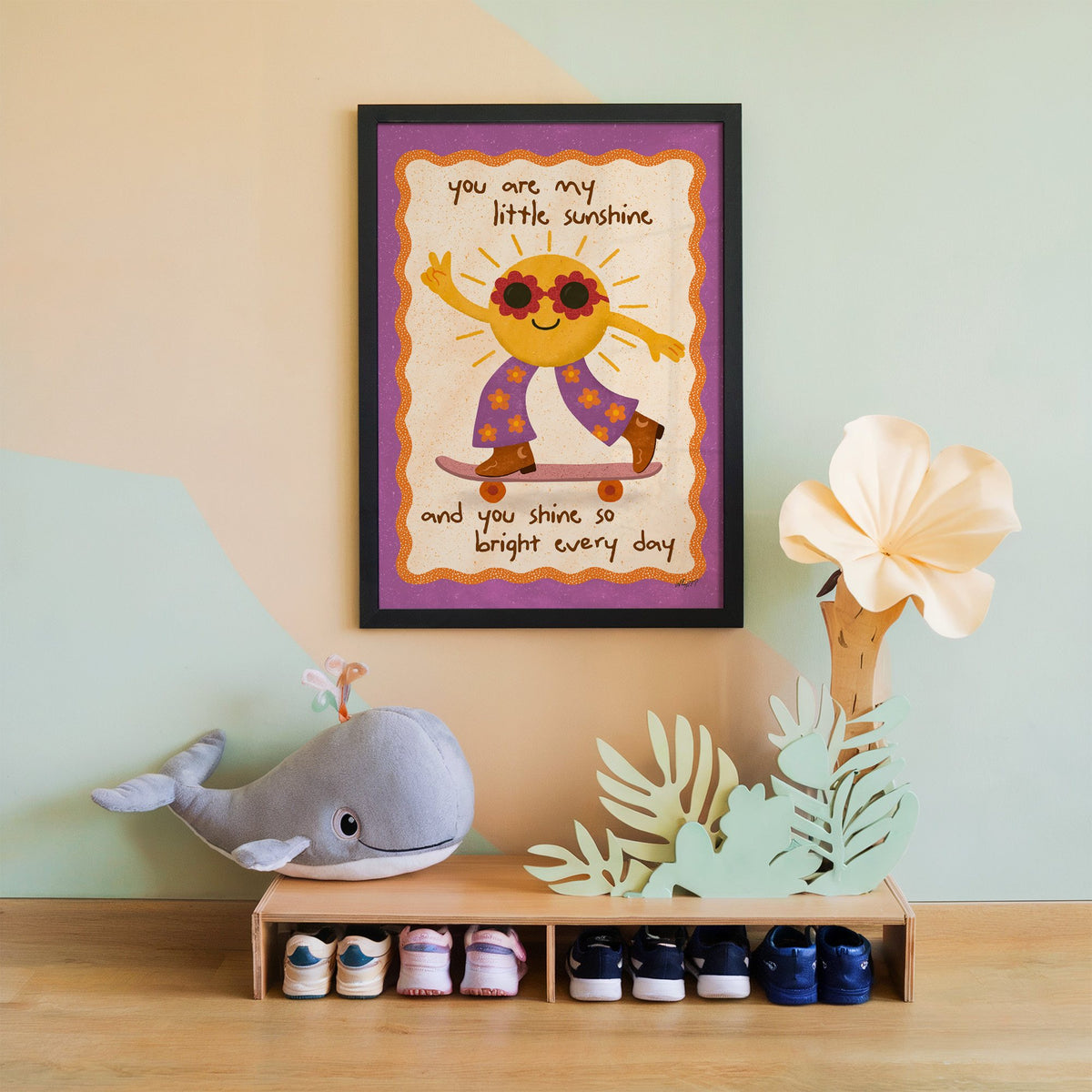 Skateboarding sun little sunshine nursery print in a black frame on a mint and peach wall above a whale plush
