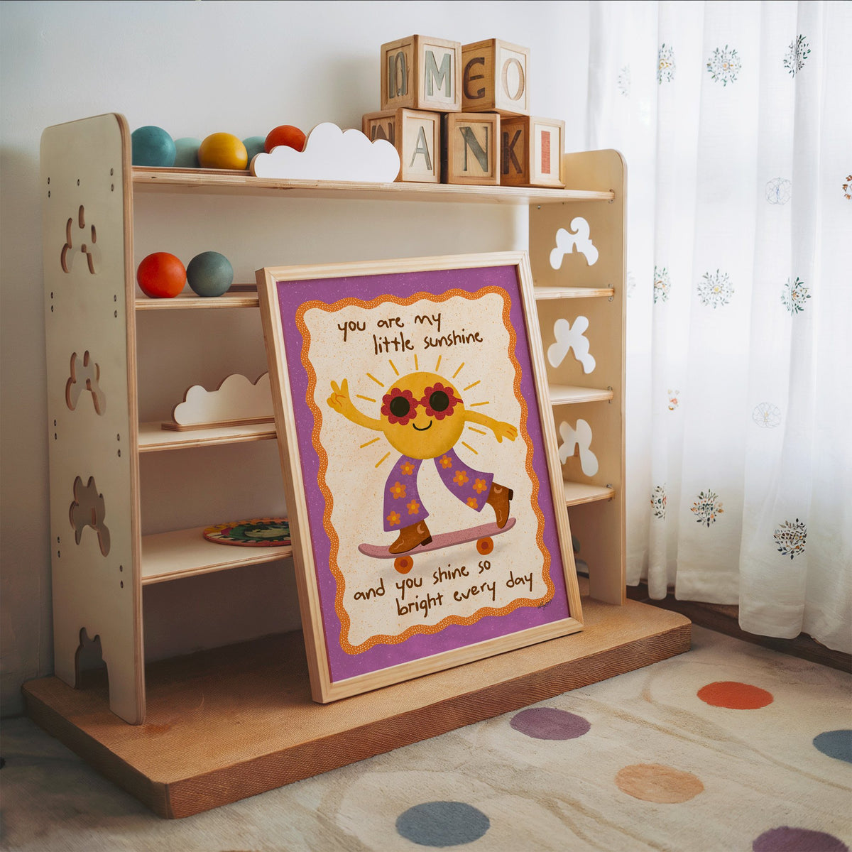 Skateboarding sun little sunshine nursery print in an oak frame leaning on a toy shelf with wooden letter blocks