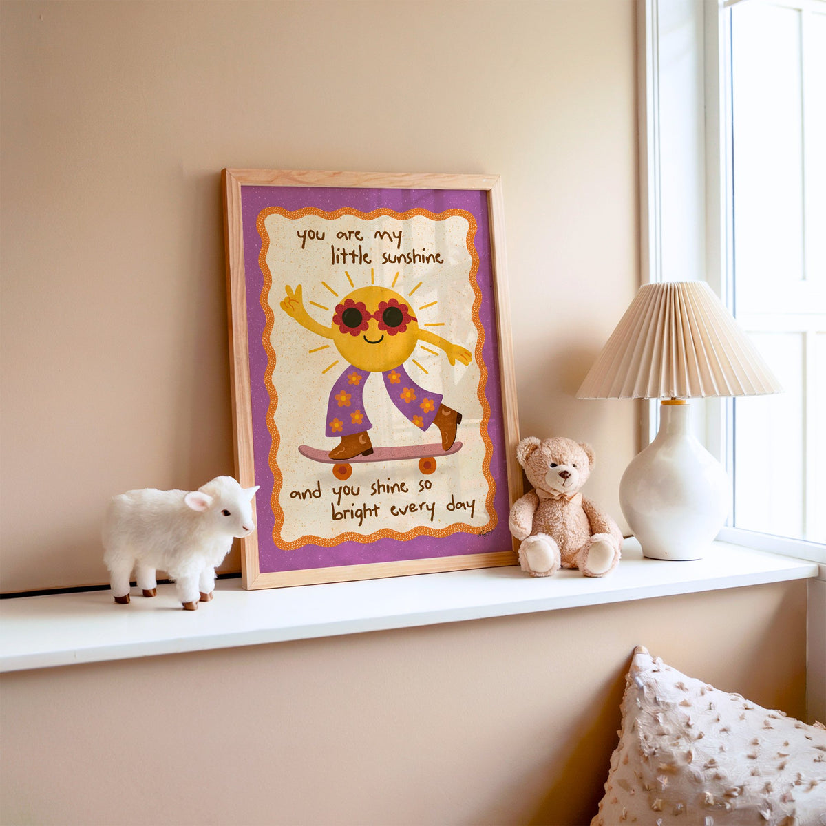 Skateboarding sun little sunshine nursery print in an oak frame on a window ledge with a toy lamb and teddy