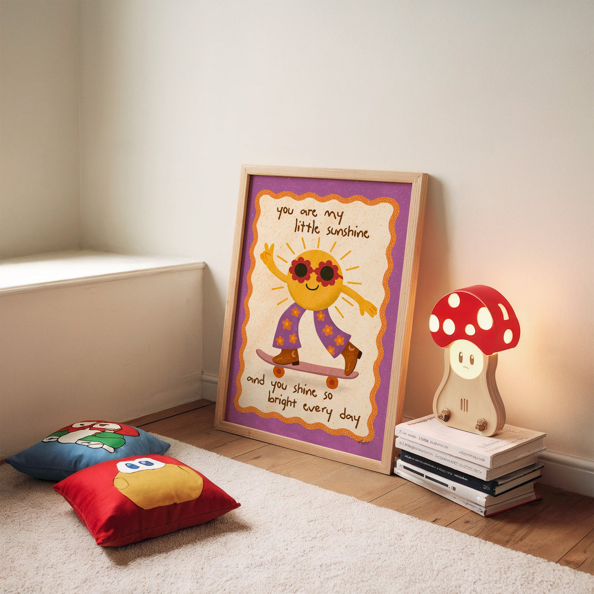 Skateboarding sun little sunshine nursery print in an oak frame leaning on a rug beside a mushroom lamp and floor cushions
