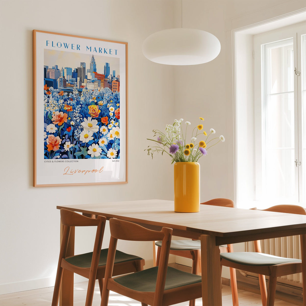 Liverpool flower market print in an oak frame above a dining table with a yellow vase and white pendant light