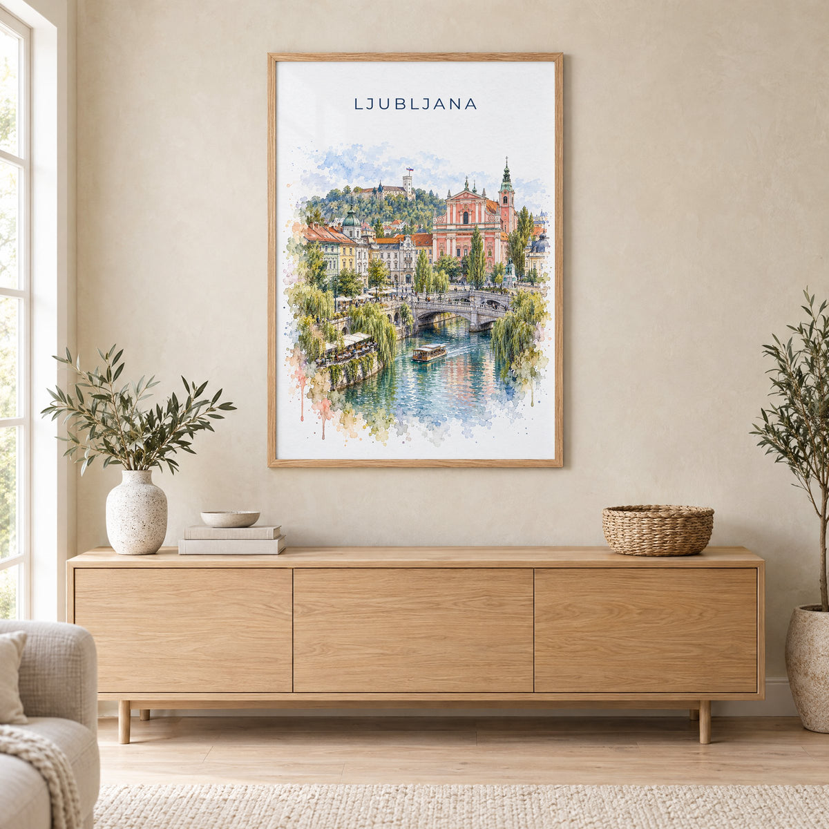 Ljubljana watercolor print in an oak frame above a light wood sideboard in a Scandinavian living room