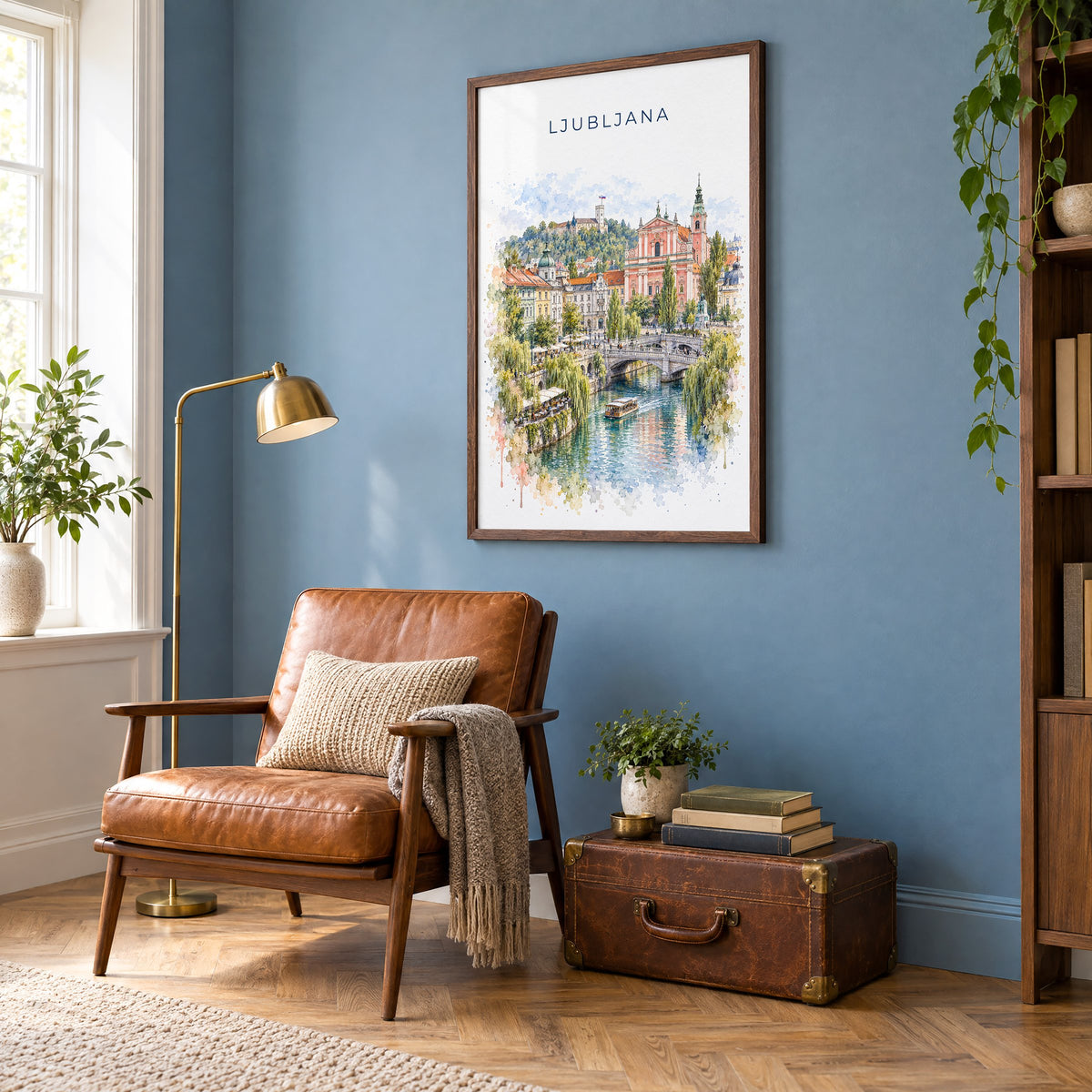 Ljubljana watercolor print in a walnut frame on a blue wall above a leather armchair in a reading nook