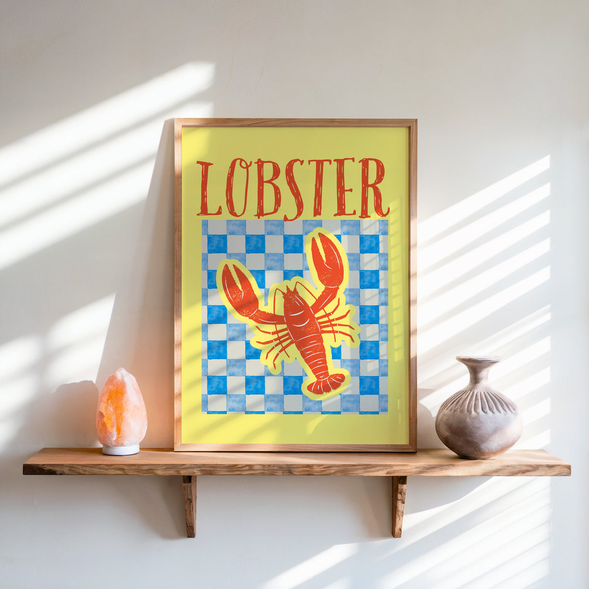 Lobster blue check print in an oak frame on a live-edge shelf beside a salt lamp