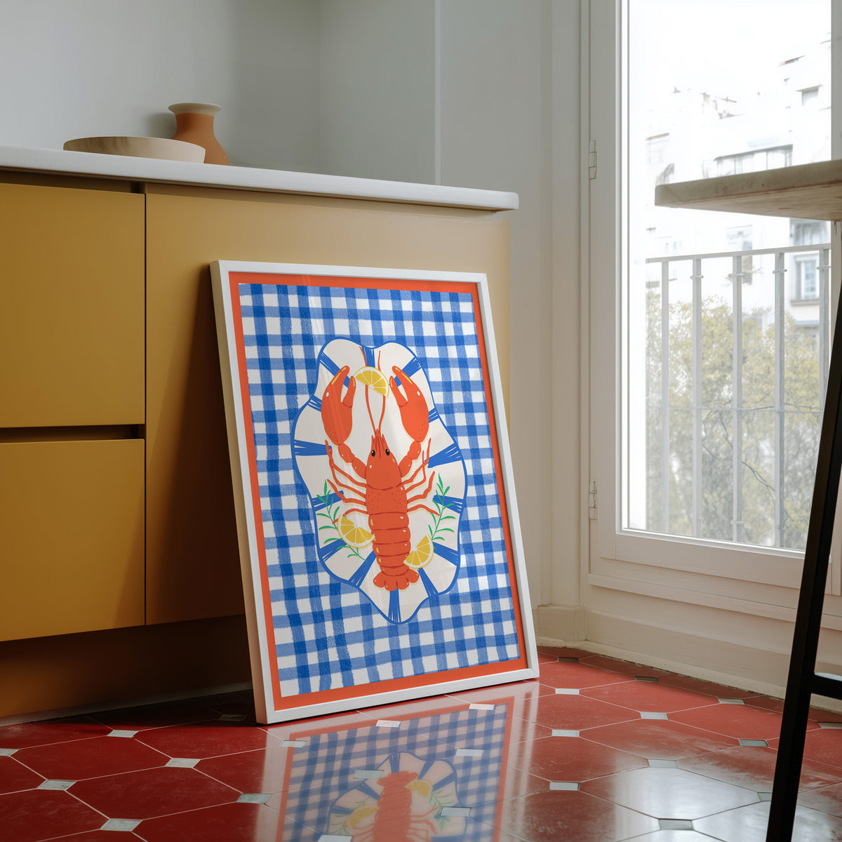Lobster gingham print in a white frame against yellow cabinets on a red tiled floor