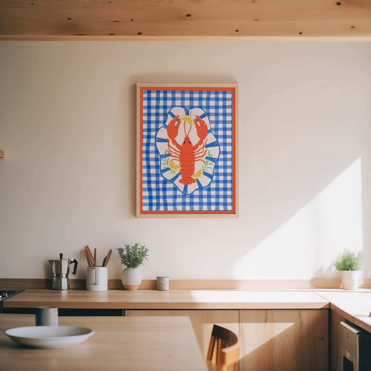 Lobster gingham print in an oak frame above a wood counter with a moka pot and herbs