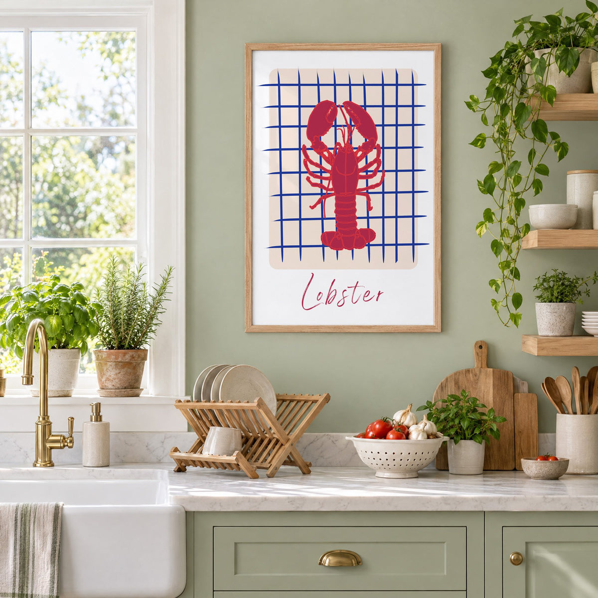 Lobster on cobalt grid print in an oak frame on a sage green kitchen wall beside a farmhouse sink and herbs