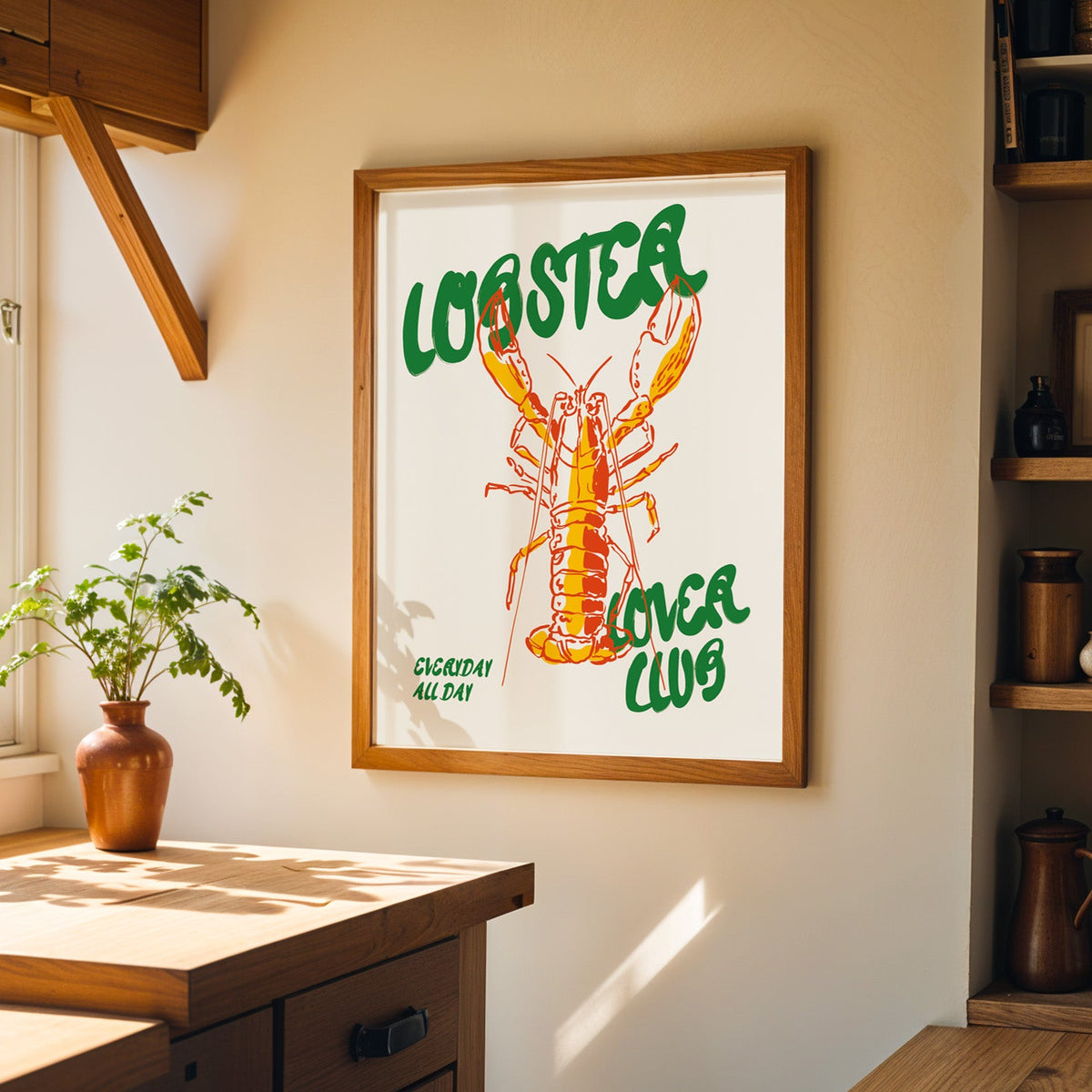Red line lobster print in a wood frame on a sunlit kitchen wall beside open shelving