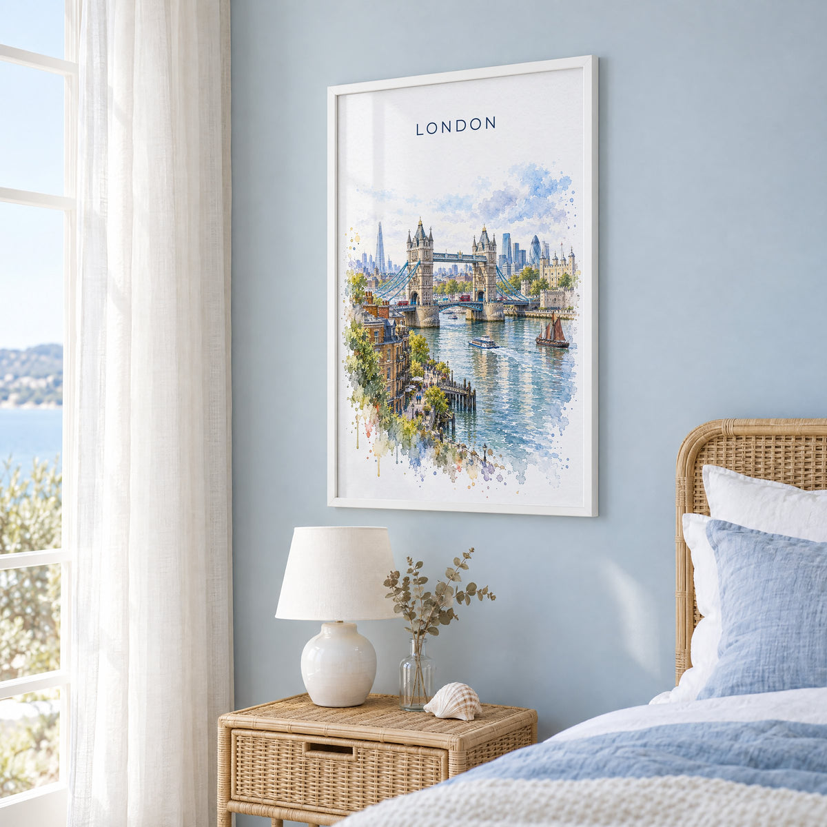 London watercolor print in a white frame on a pale blue wall beside a rattan bed in a coastal bedroom