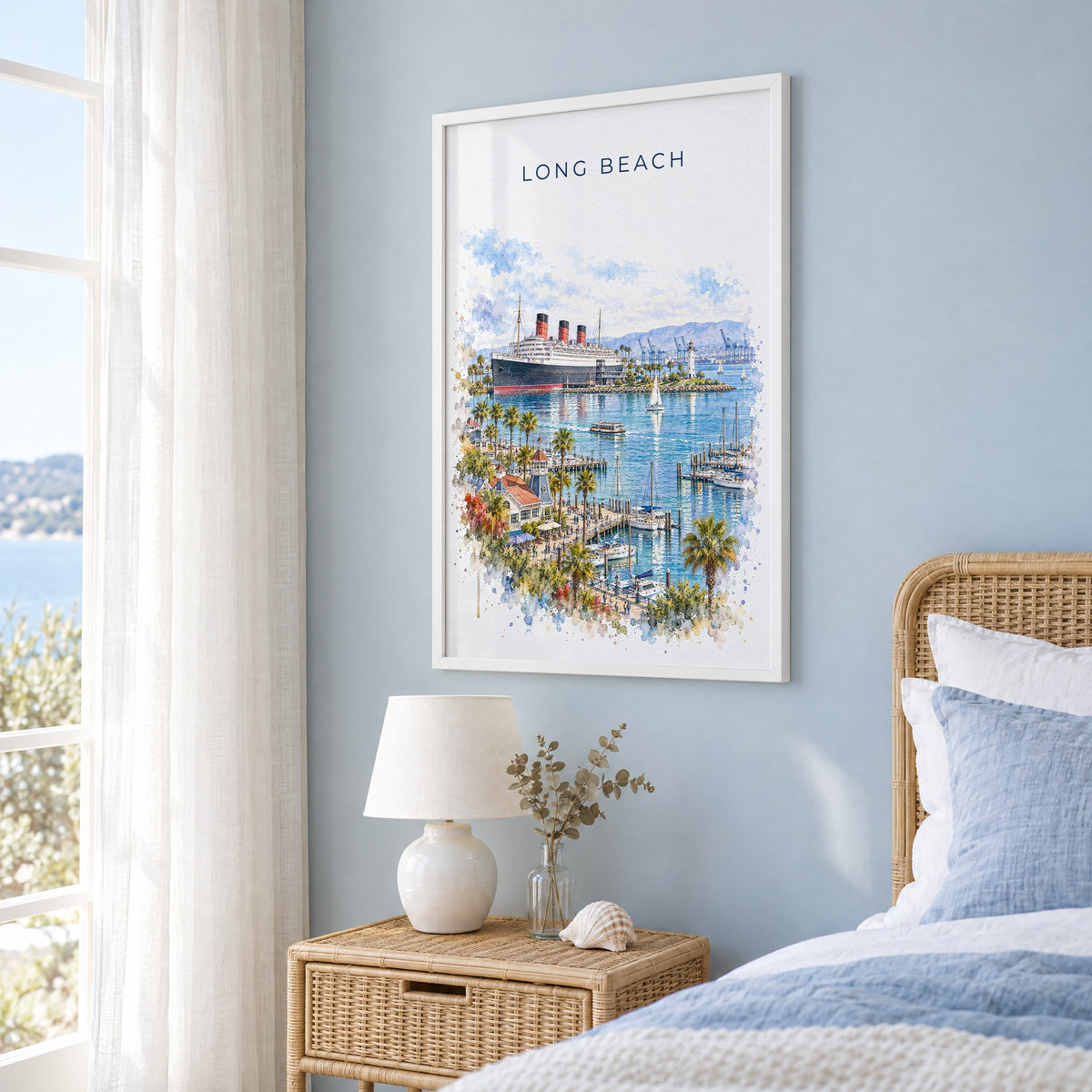 Long Beach watercolor print in a white frame on a pale blue wall beside a rattan bed in a coastal bedroom
