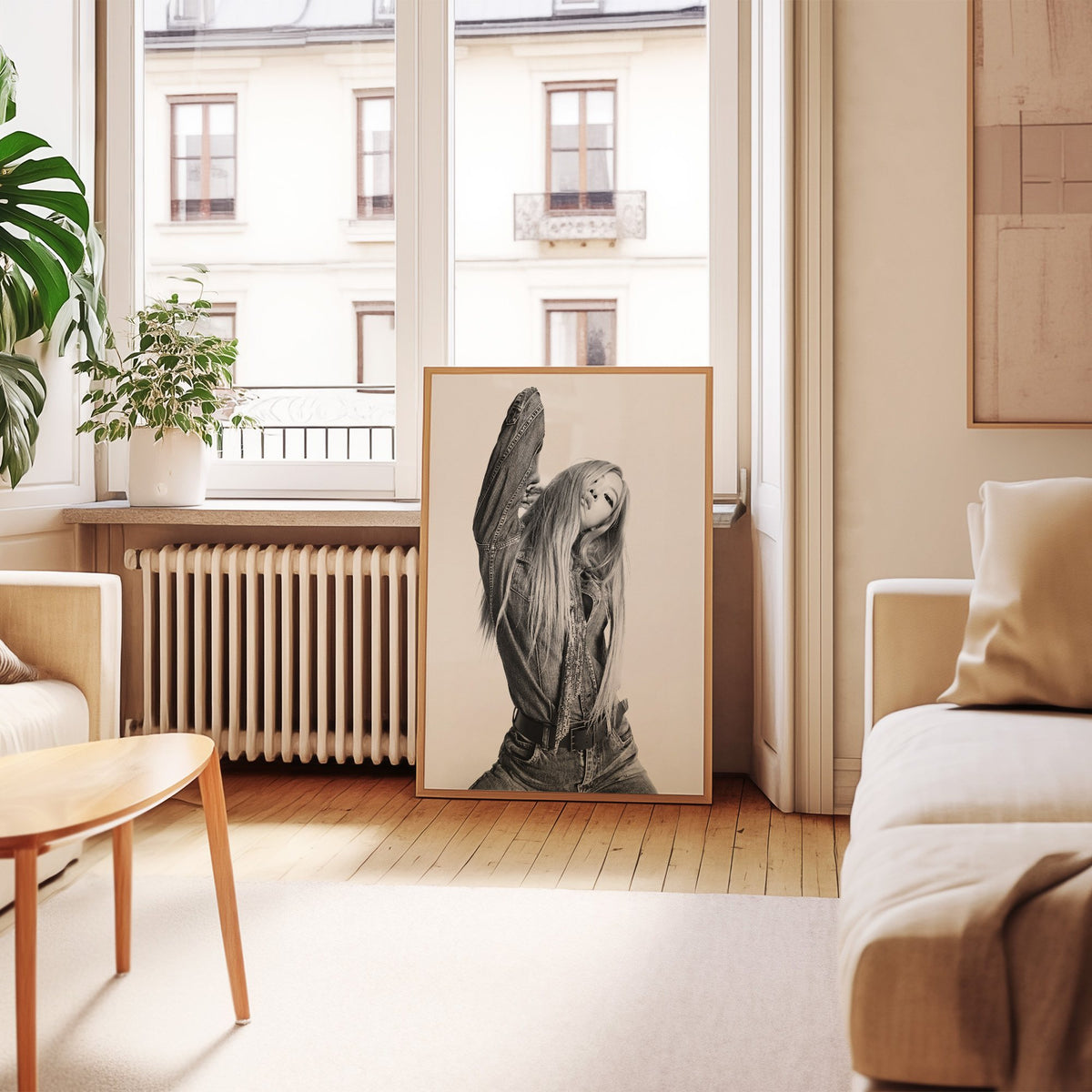 Model in oversized denim jacket, arm raised print in an oak frame leaning by a French window in a living room