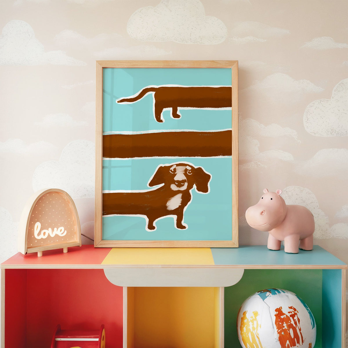 Extra long dachshund in three rows nursery print in an oak frame on a rainbow toy shelf against cloud wallpaper