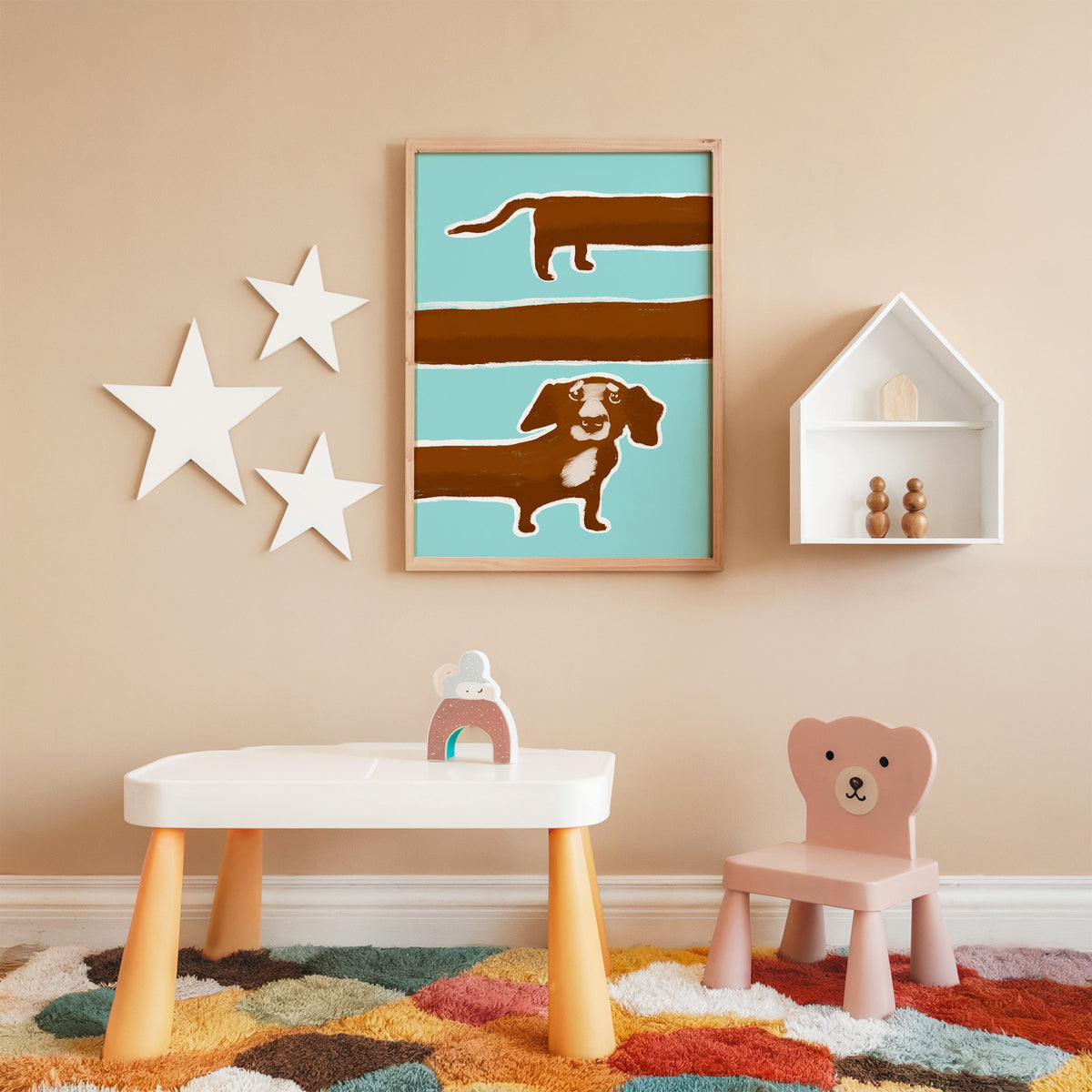 Extra long dachshund in three rows nursery print in an oak frame on a peach wall above a kids table with wall stars