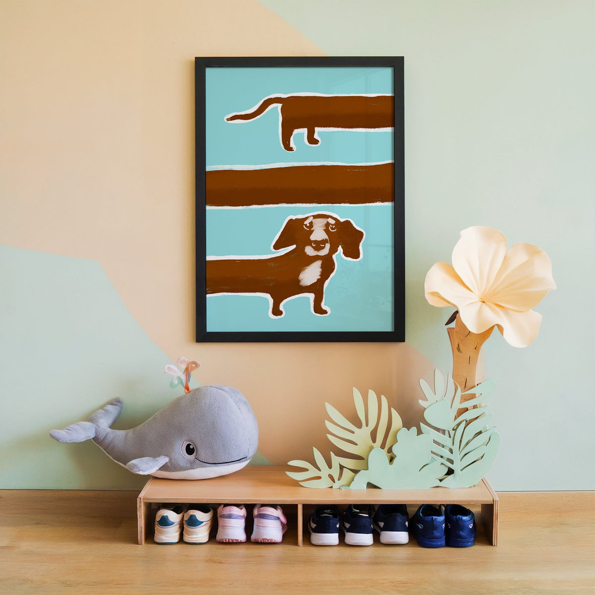 Extra long dachshund in three rows nursery print in a black frame on a mint and peach wall above a whale plush