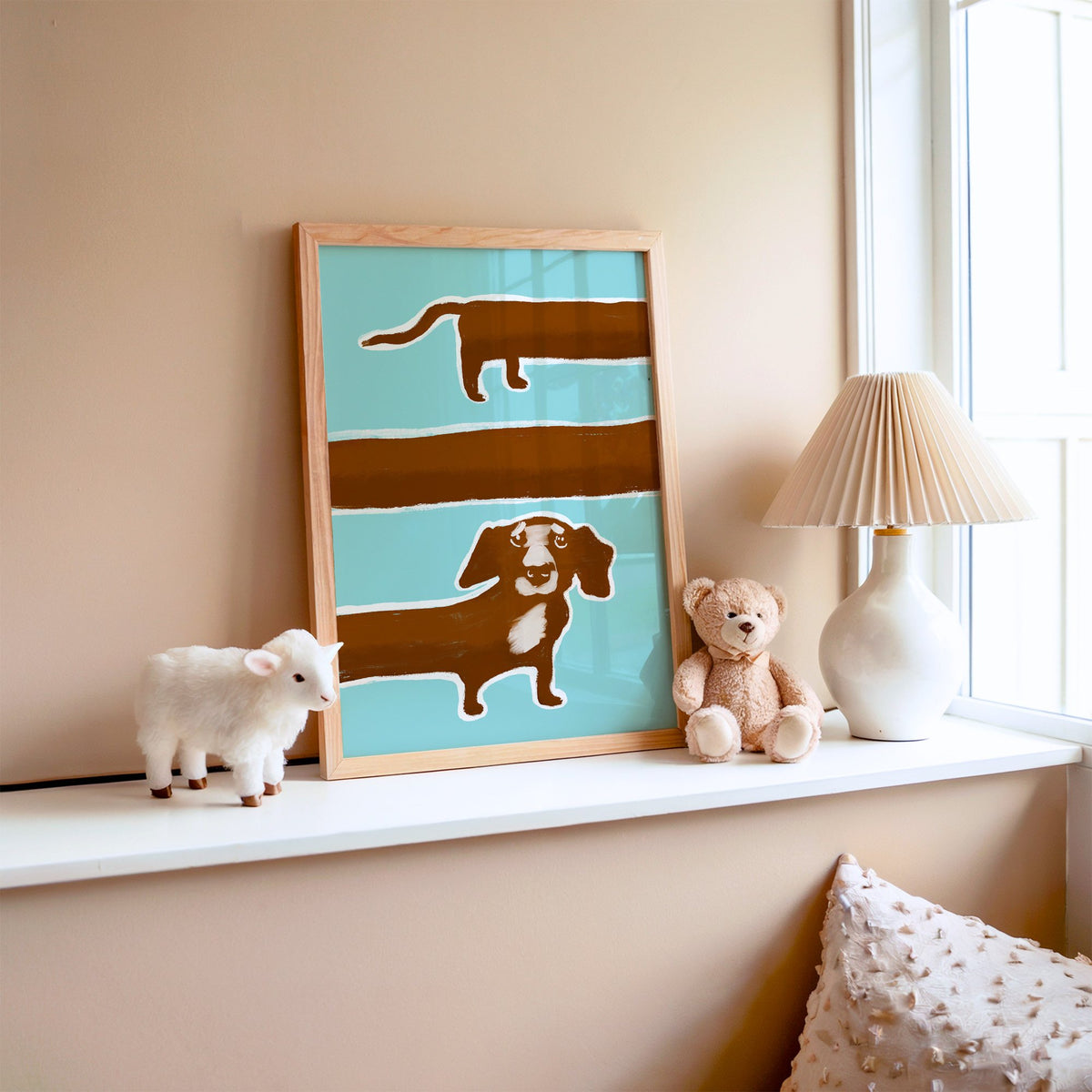 Extra long dachshund in three rows nursery print in an oak frame on a window ledge with a toy lamb and teddy