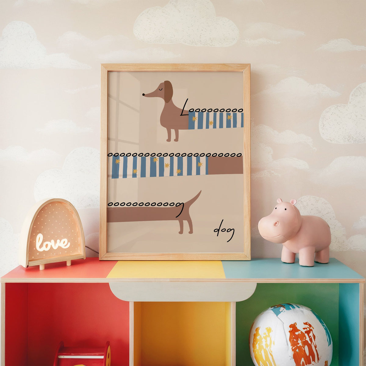Long dog dachshund sweater nursery print in an oak frame on a rainbow toy shelf against cloud wallpaper