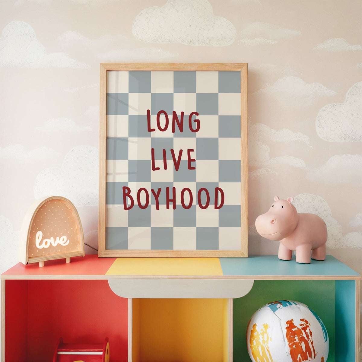 Long live boyhood checker nursery print in an oak frame on a rainbow toy shelf against cloud wallpaper