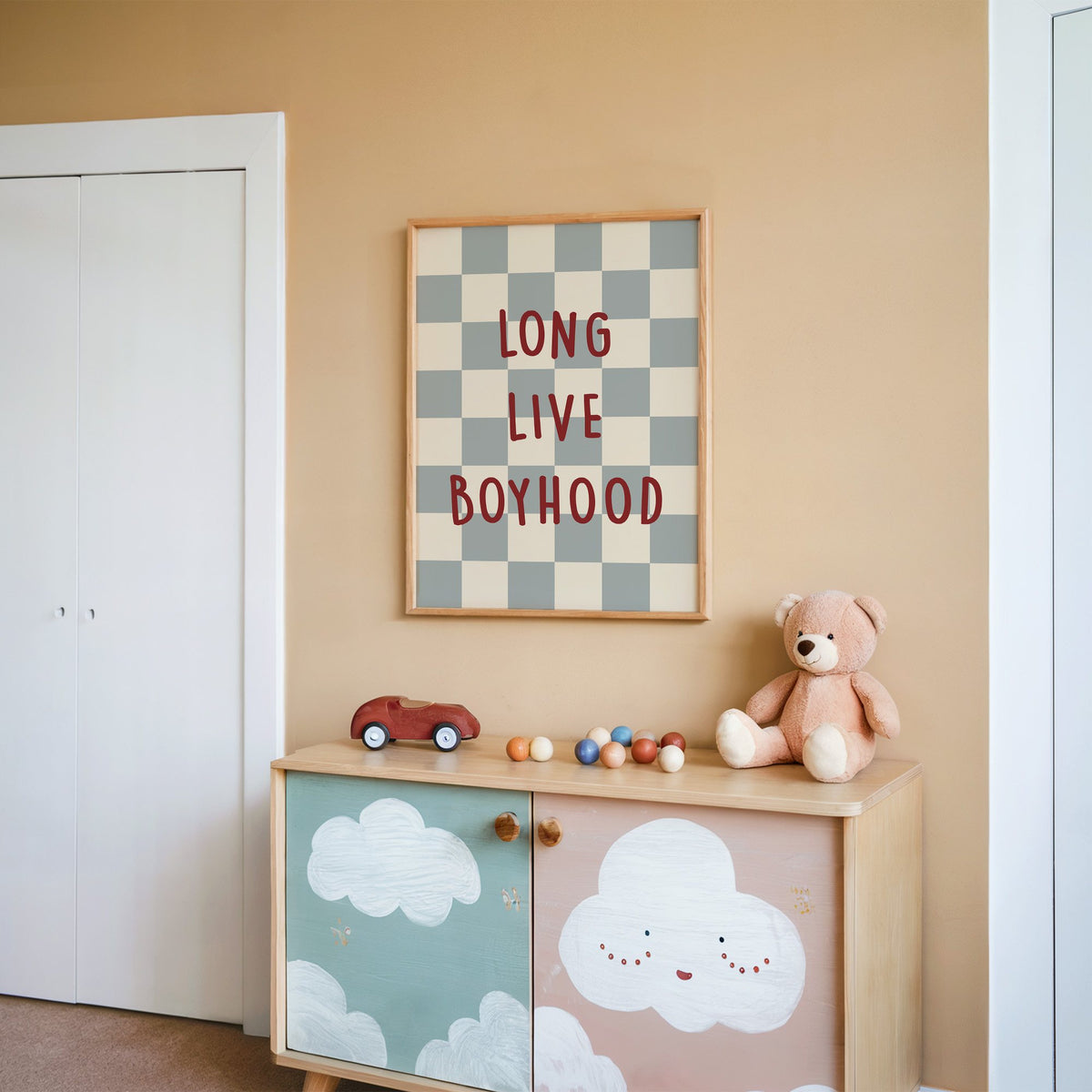 Long live boyhood checker nursery print in an oak frame on a peach wall above a cloud-painted cabinet