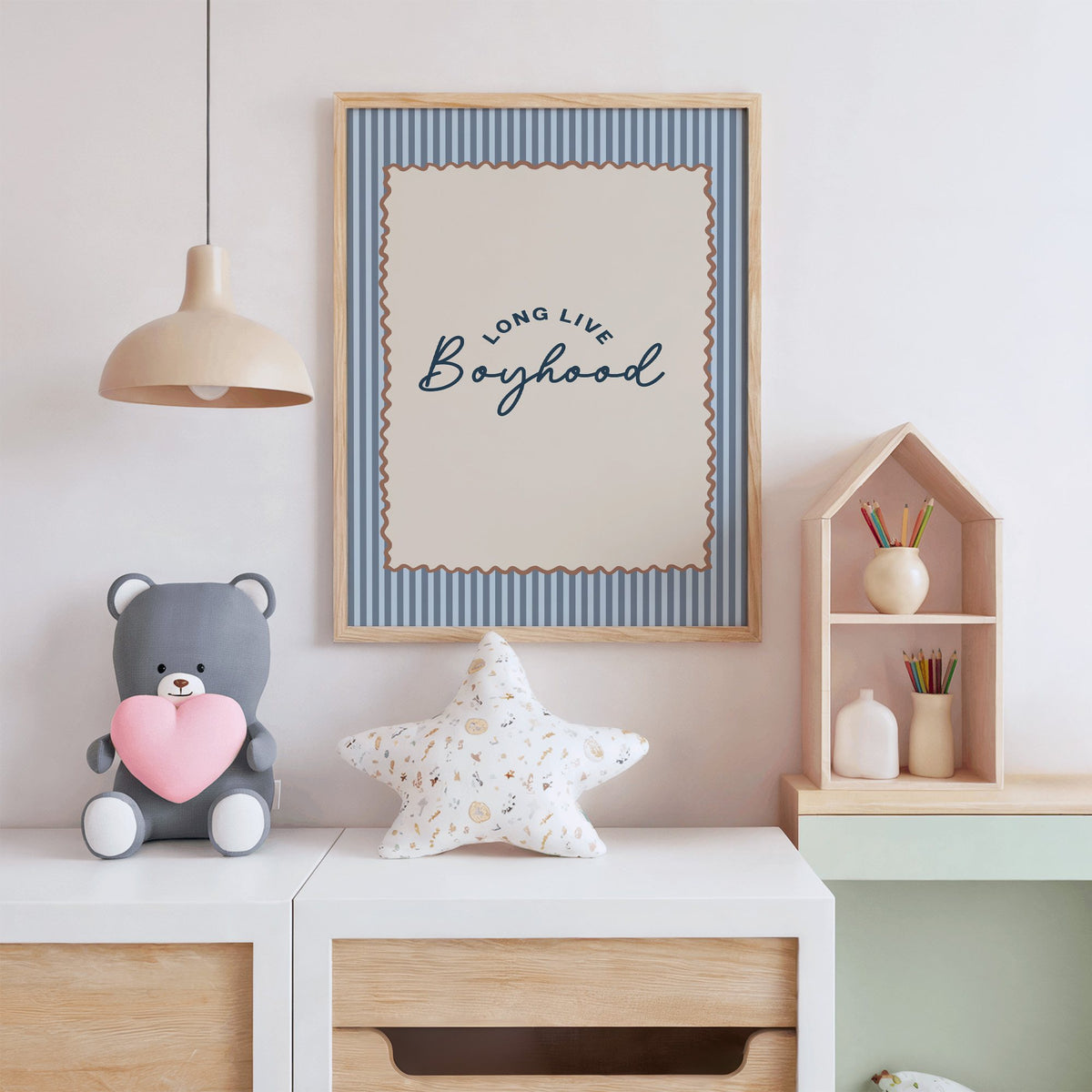 Long live boyhood nursery print in an oak frame above a white dresser with a star pillow and house shelf