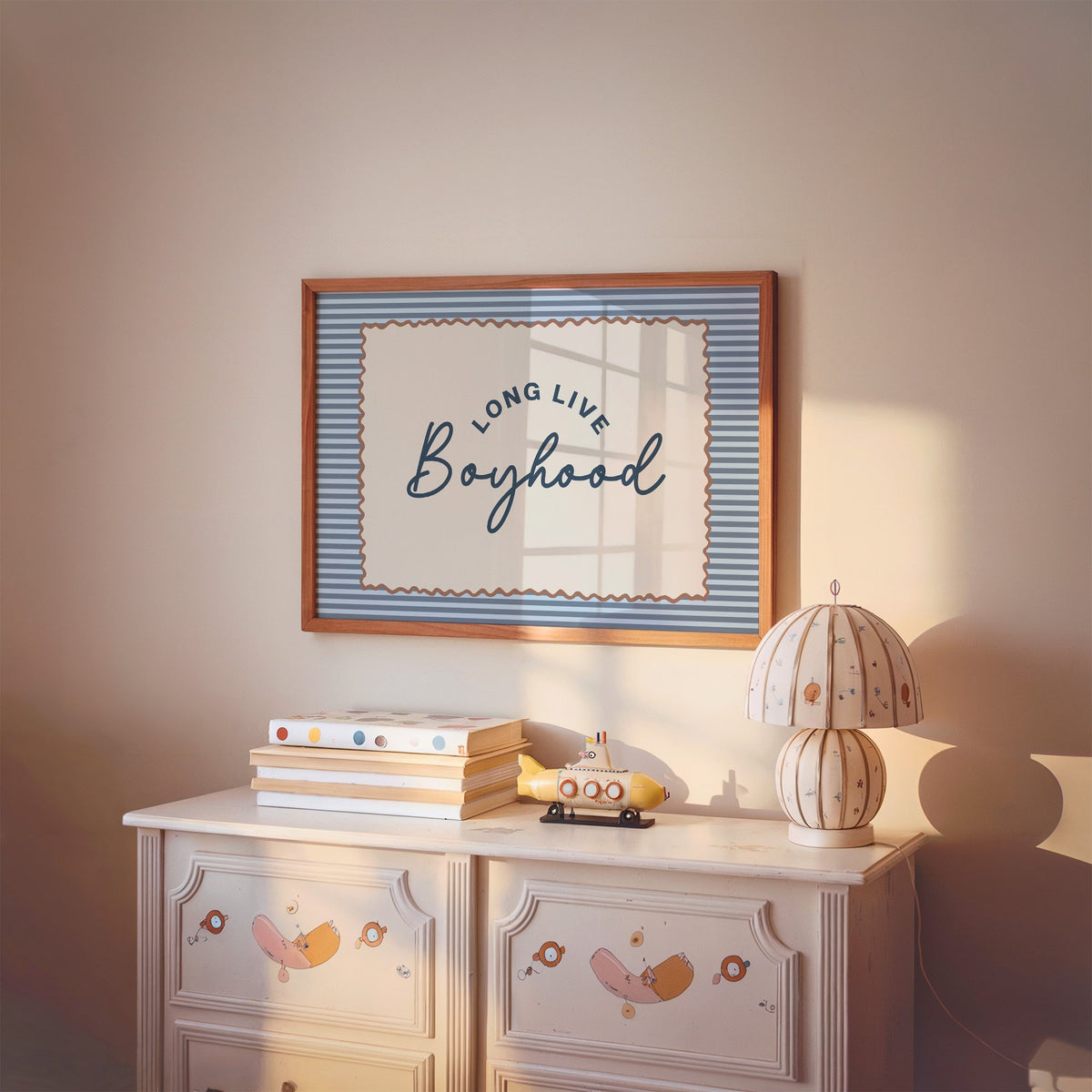 Landscape long live boyhood nursery print in a cherry wood frame above a painted dresser and lamp