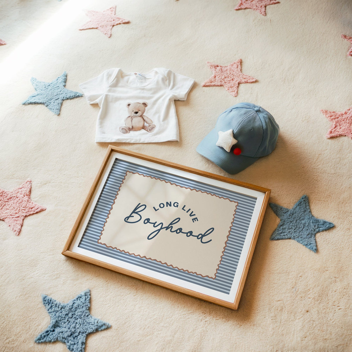 Landscape long live boyhood nursery print in a matted oak frame on a star rug with a baby tee