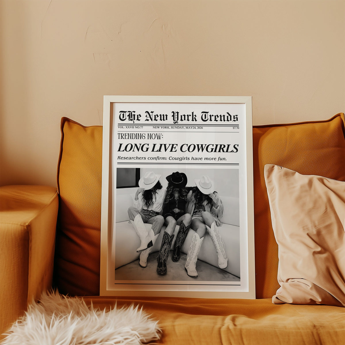 Three cowgirls on white sofa mock newspaper print in a white frame leaning on a mustard velvet sofa