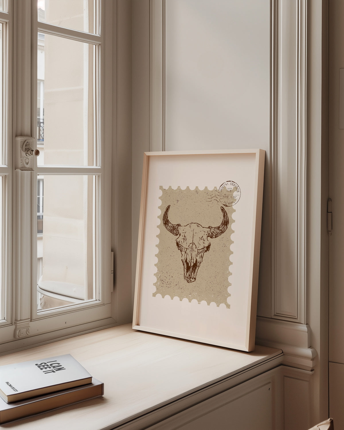 Longhorn skull stamp print in a pale wood frame on a sunlit window ledge