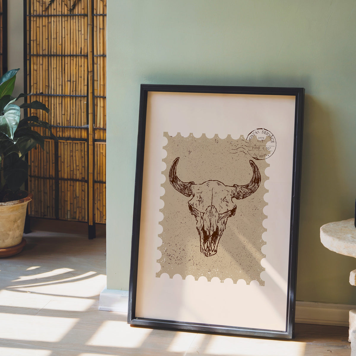 Longhorn skull stamp print in a black frame leaning against a sage green wall