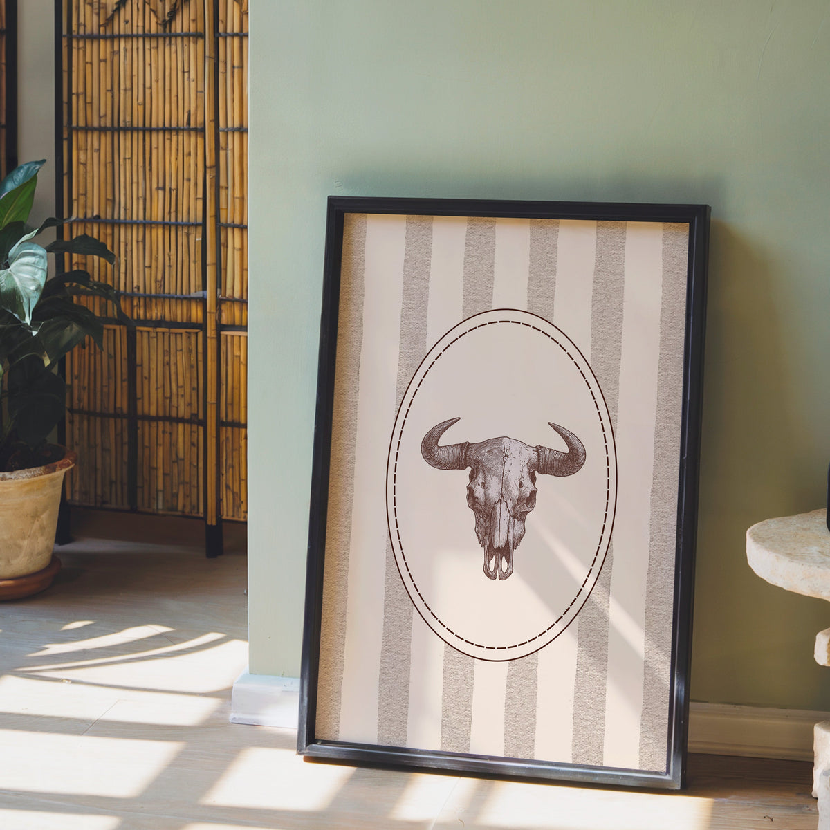 Longhorn skull cameo print in a black frame leaning against a sage green wall