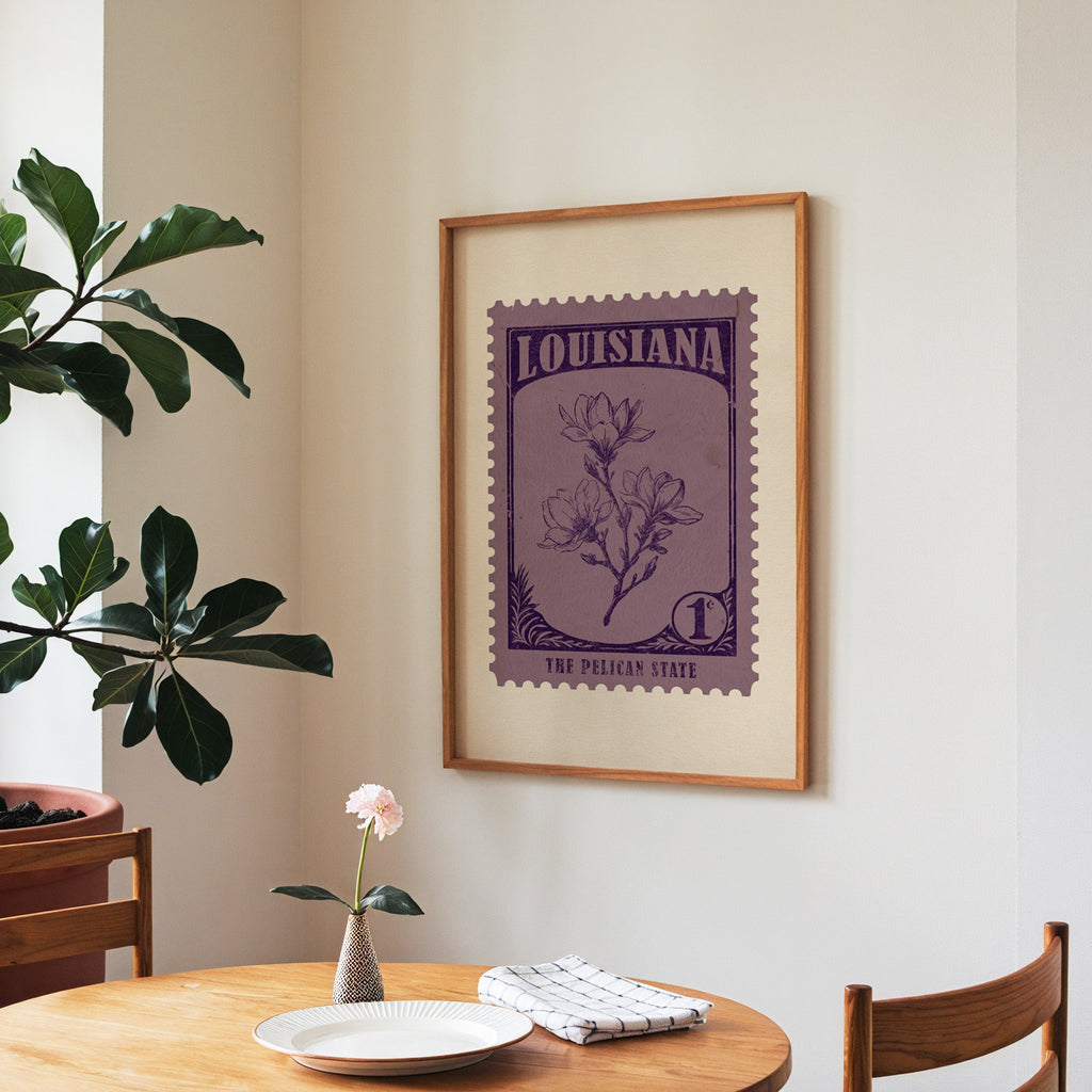 Louisiana state flower print framed above a round wooden table with a single bloom in a vase and books