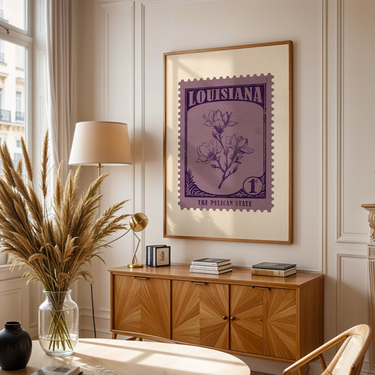 Louisiana stamp print framed above a wooden sideboard, pampas grass in a glass vase and a floor lamp